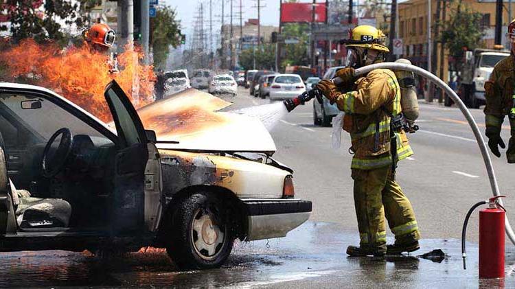 消防员在着火的汽车引擎盖下喷水.