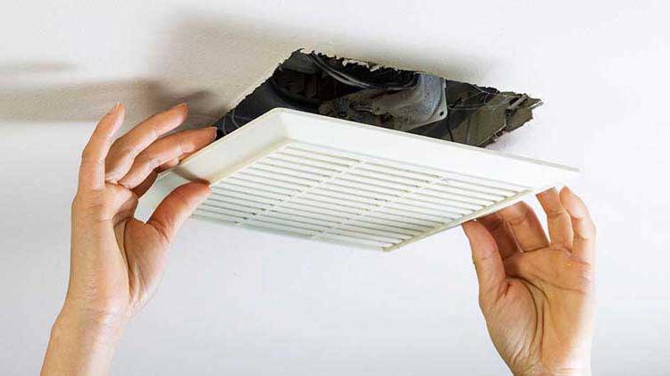 Two hands installing ceiling vent.
