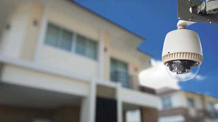 A remote home monitoring camera is attached to the outside of a residential building.
