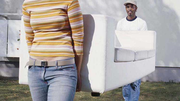 Two people carrying a couch after getting moving insurance.