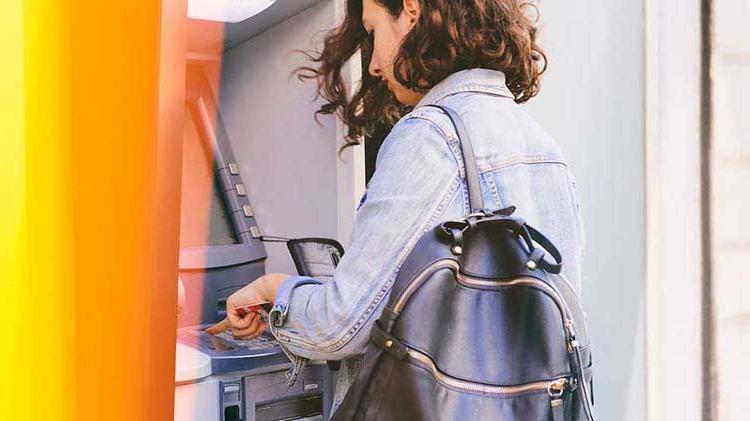 Woman easily accessing her checking account funds by using an ATM.