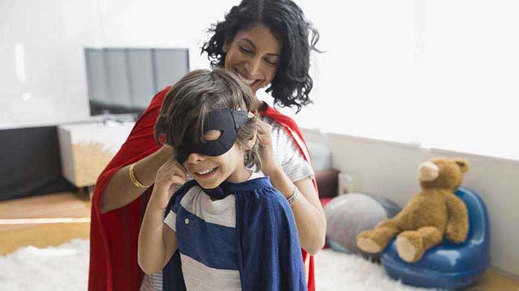 Mom helping her son put on a costume mask.