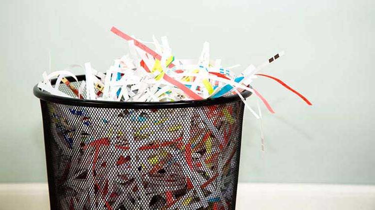 Black waste basket full of shredded paper.