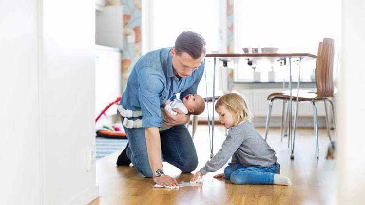 Father practicing household safety by helping his young daughter clean up a spill.