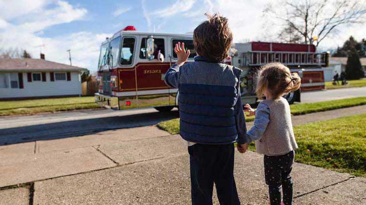 Kids waving at a fire truck after practicing their fire evacuation plan.