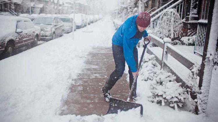Man shoveling a snow covered sidewalk.