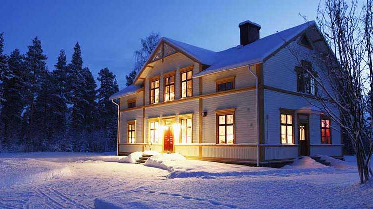 黄昏时雪景中的一间灯火通明的房子