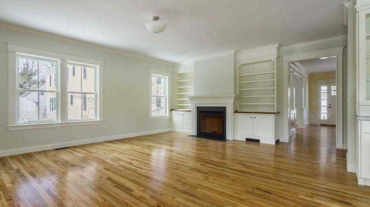 Empty house living room interior with wood floors and a fireplace and built-in bookshelves.