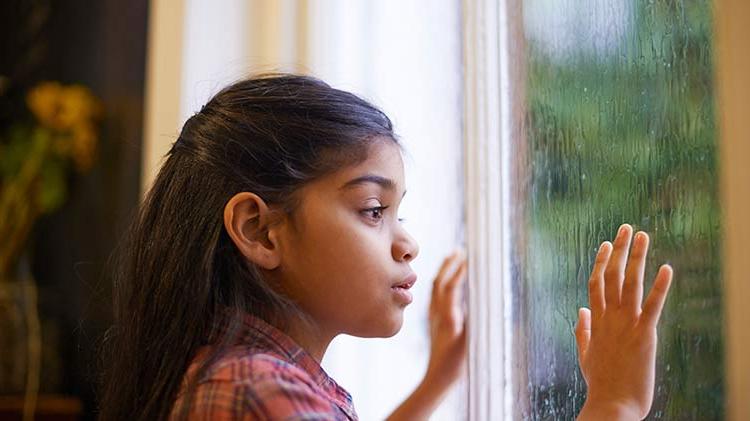 Girl safely looking out a rainy window