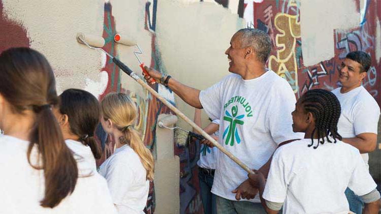 Group of people giving back to the community by painting over graffiti on a wall.