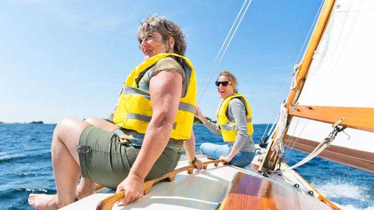 两名妇女在船上穿着救生衣练习划船安全.