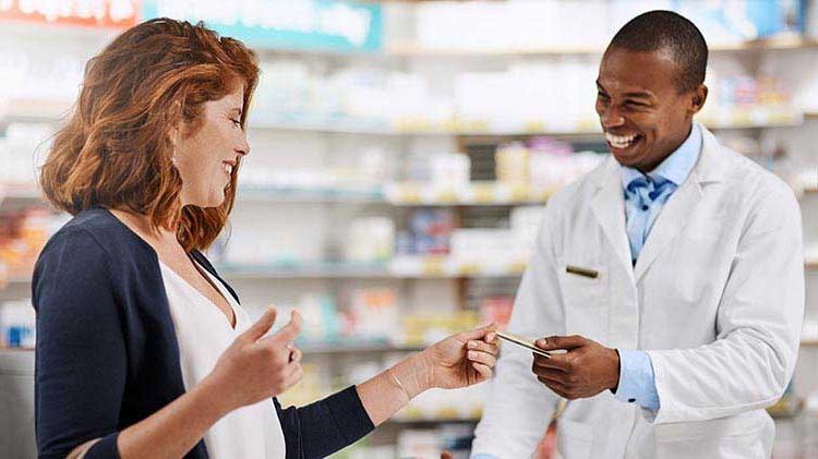 Woman handing credit card to pharmacist to pay.