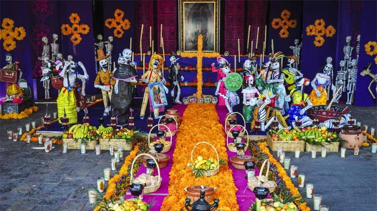 A Day of the Dead altar with flowers, Catrines and other offerings.