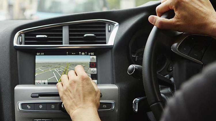 Driver interacting with touch screen on car dashboard.