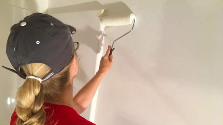 Woman in red shirt painting a wall during home maintenance.
