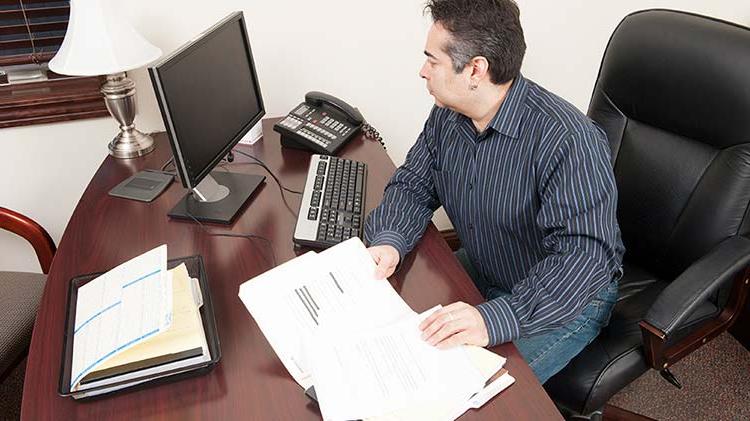 A small business owner sits at his desk working on his inventory