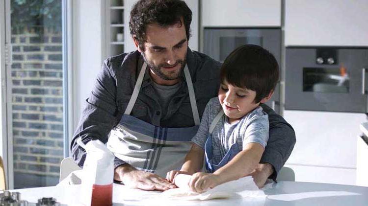 Man rolling dough with his child.