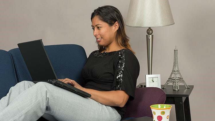 A woman reclines on the couch with her laptop completing a screen capture.
