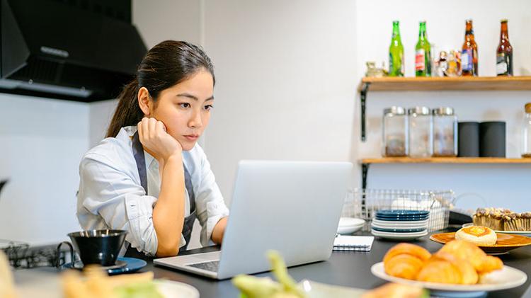 A woman sits at her computer thinking about her business.
