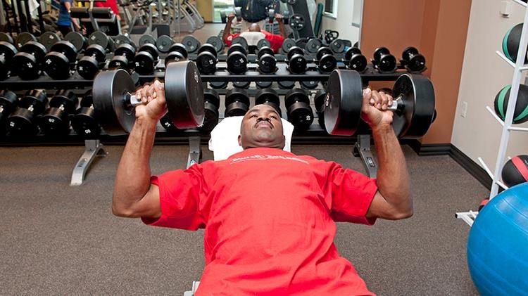 Using his company perks, a man lifts weights at the gym.
