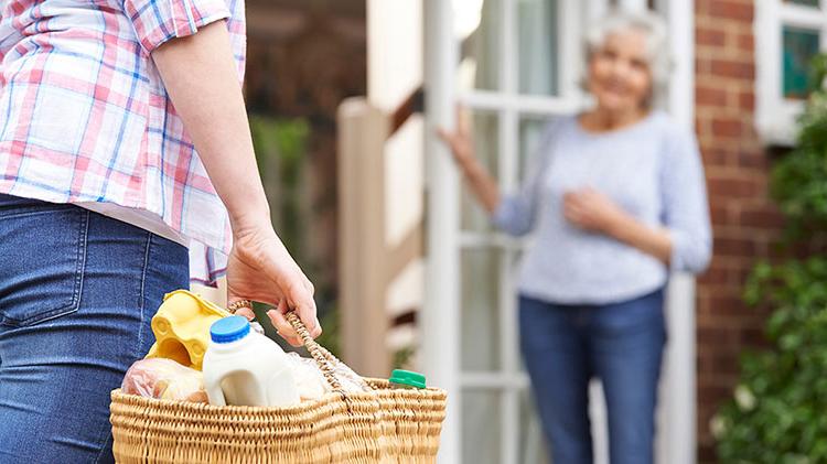 Carrying a basket of items to an elderly neighbor.