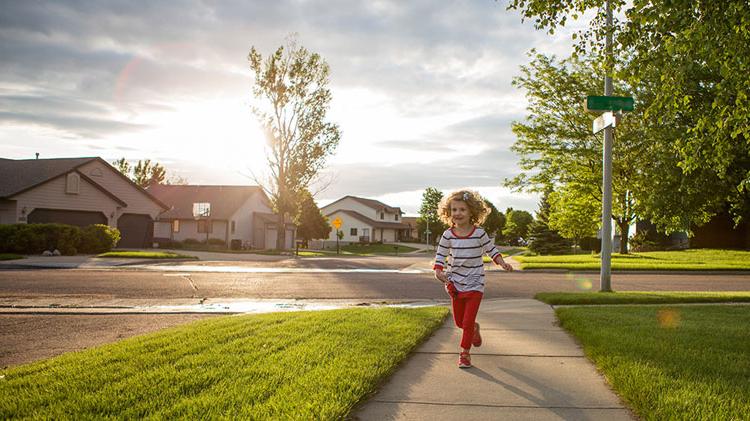 Child running in a neighborhood made safer by neighborhood social media network.