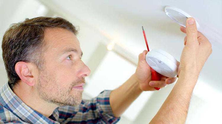 Man practicing fire safety and prevention by installing a smoke detector.