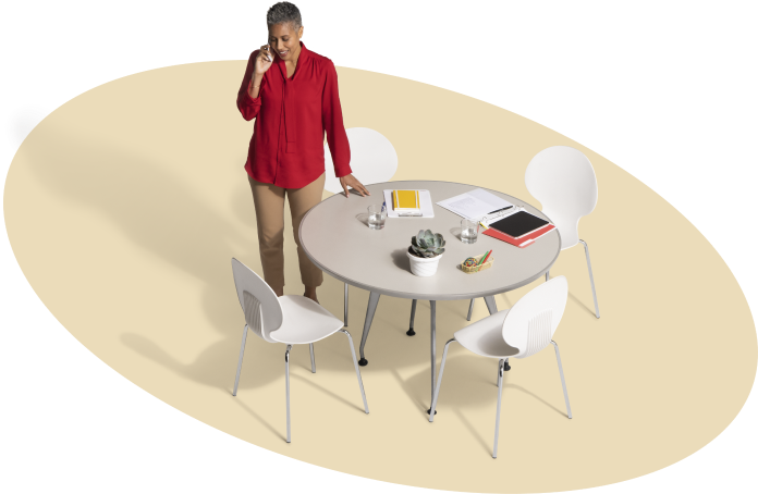 Standing next to a round table inside a beige oval, a State Farm agent takes a call for an auto insurance quote.