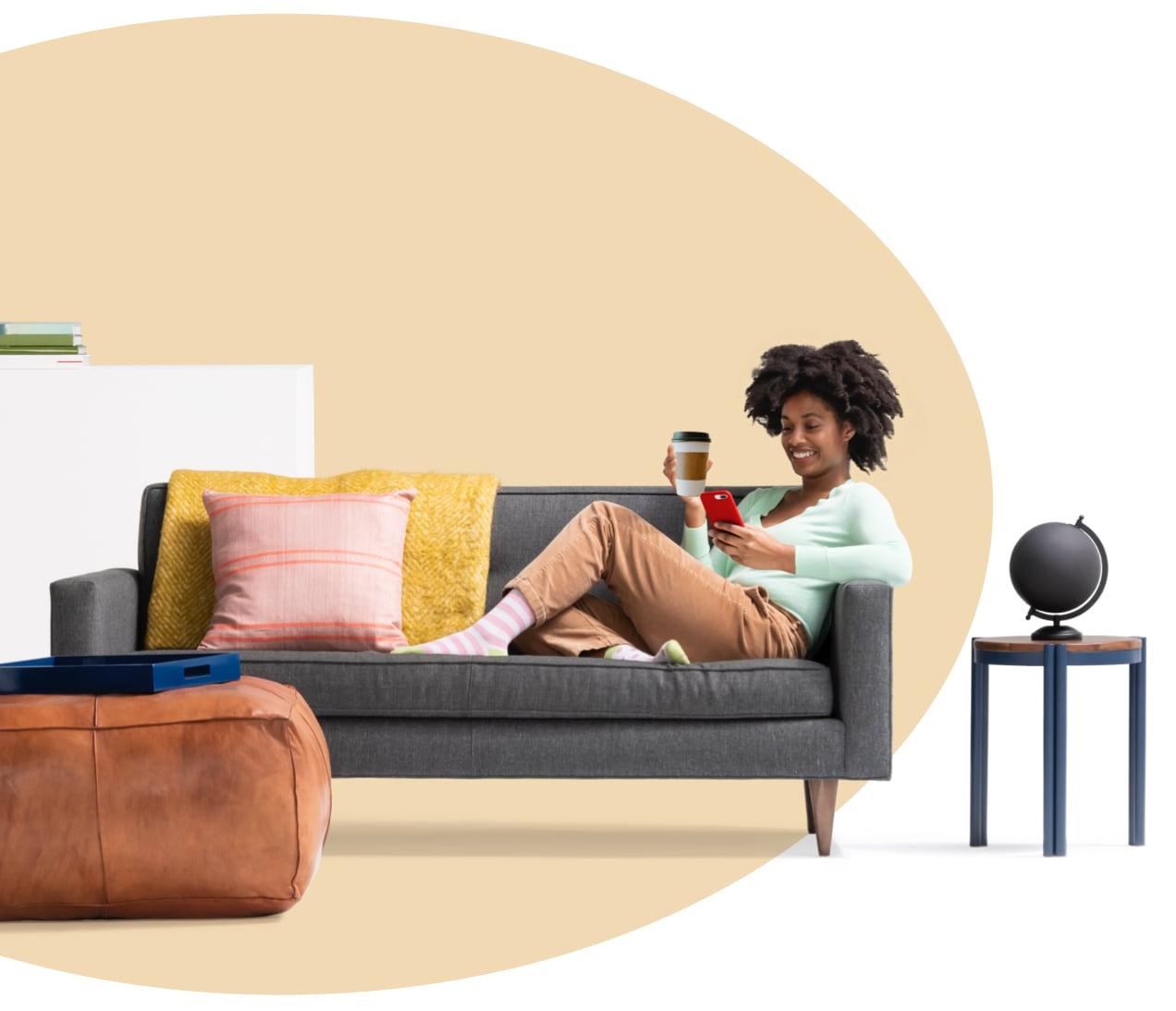 一个女人坐在沙发上，端着咖啡，一边用iPhone看租房pp王者电子官网的内容. 边桌上放着一个地球仪.